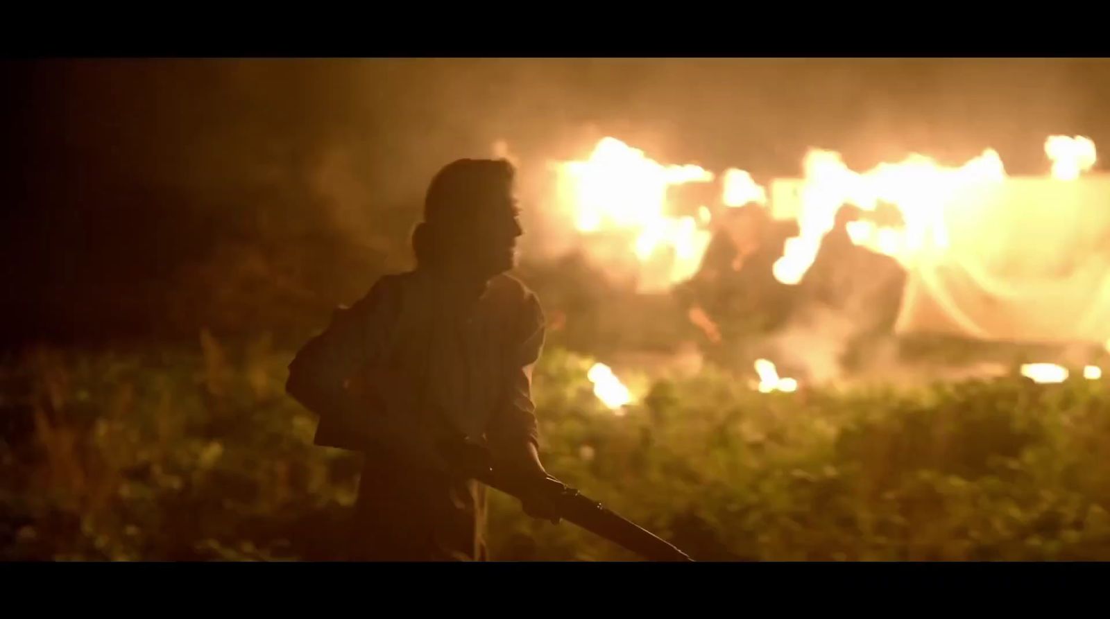 a man holding a baseball bat in front of a fire