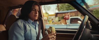 a woman sitting in a car eating a sandwich