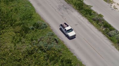 a white truck driving down a road next to a lush green field