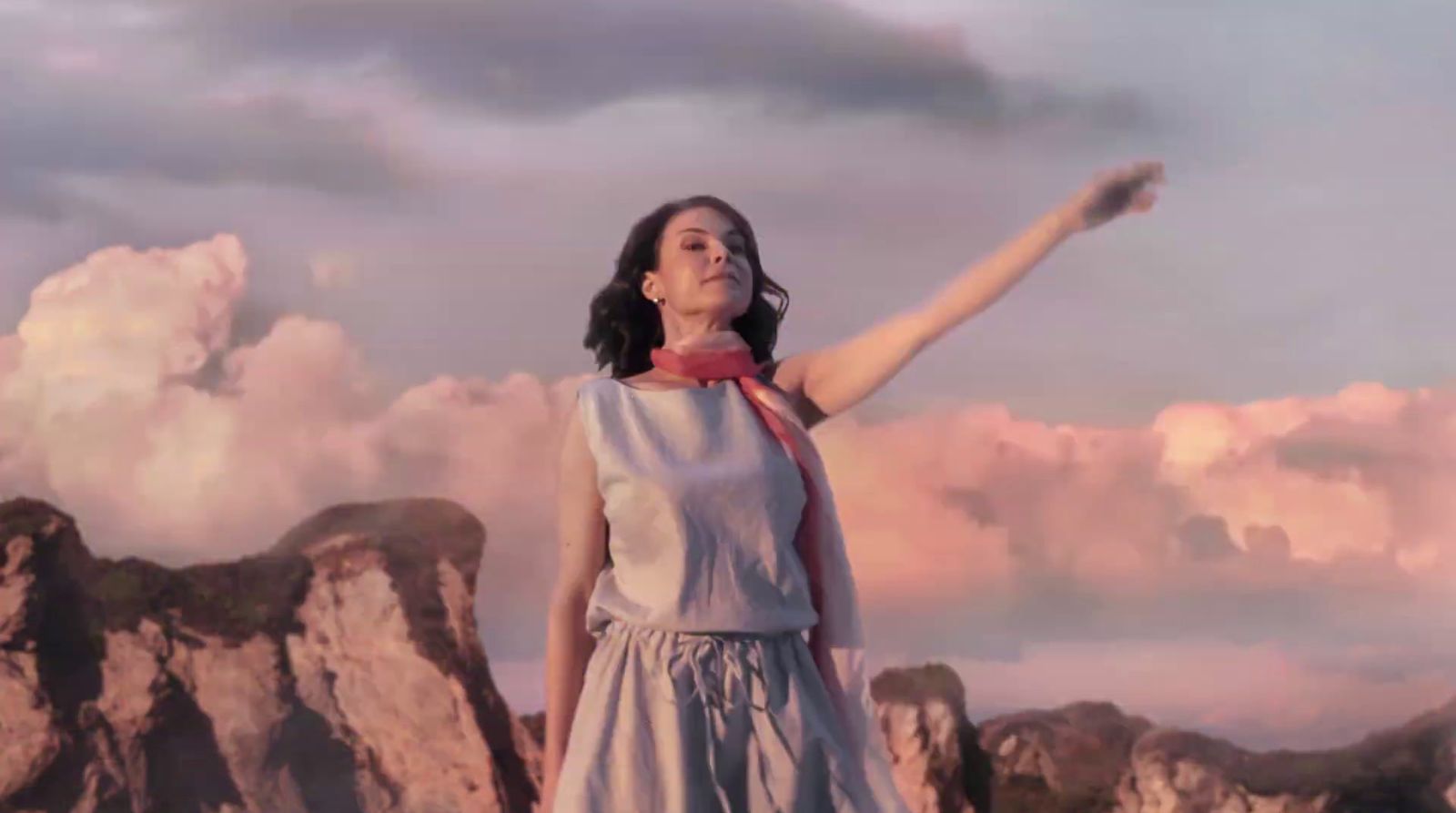 a woman standing on top of a mountain with her arms in the air