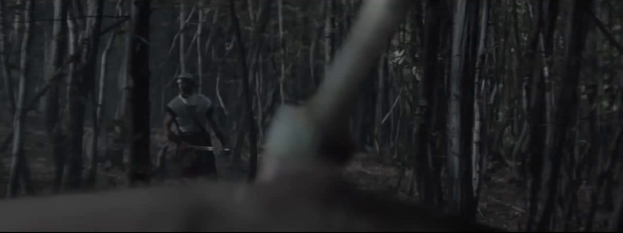 a man walking through a forest holding a gun