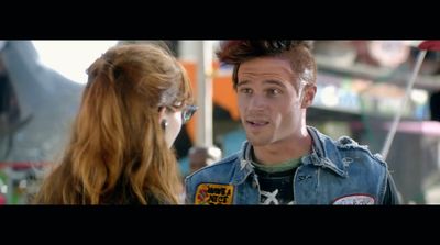 a man in a jean jacket talking to a woman