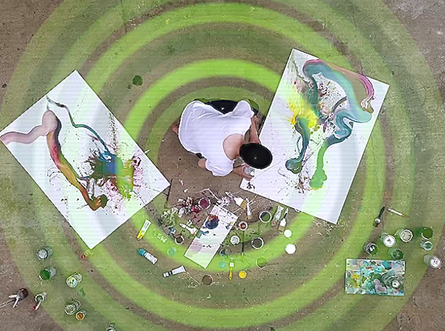 a man sitting on the ground next to two paintings