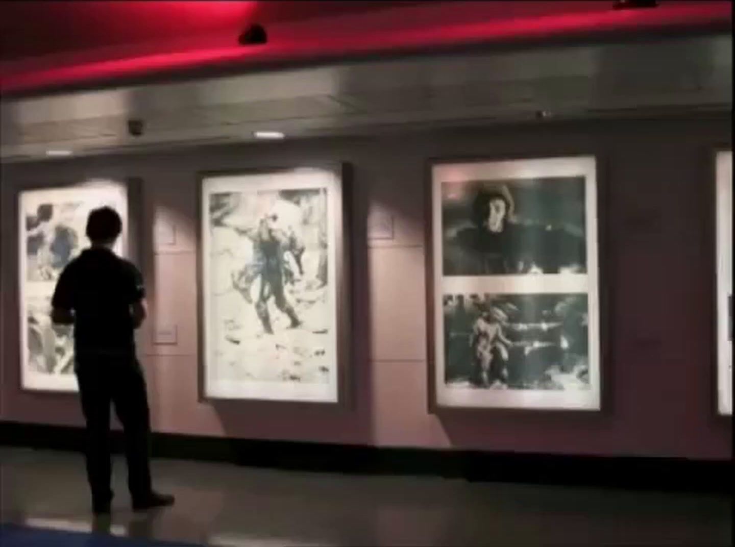 a man standing in front of a wall with pictures on it