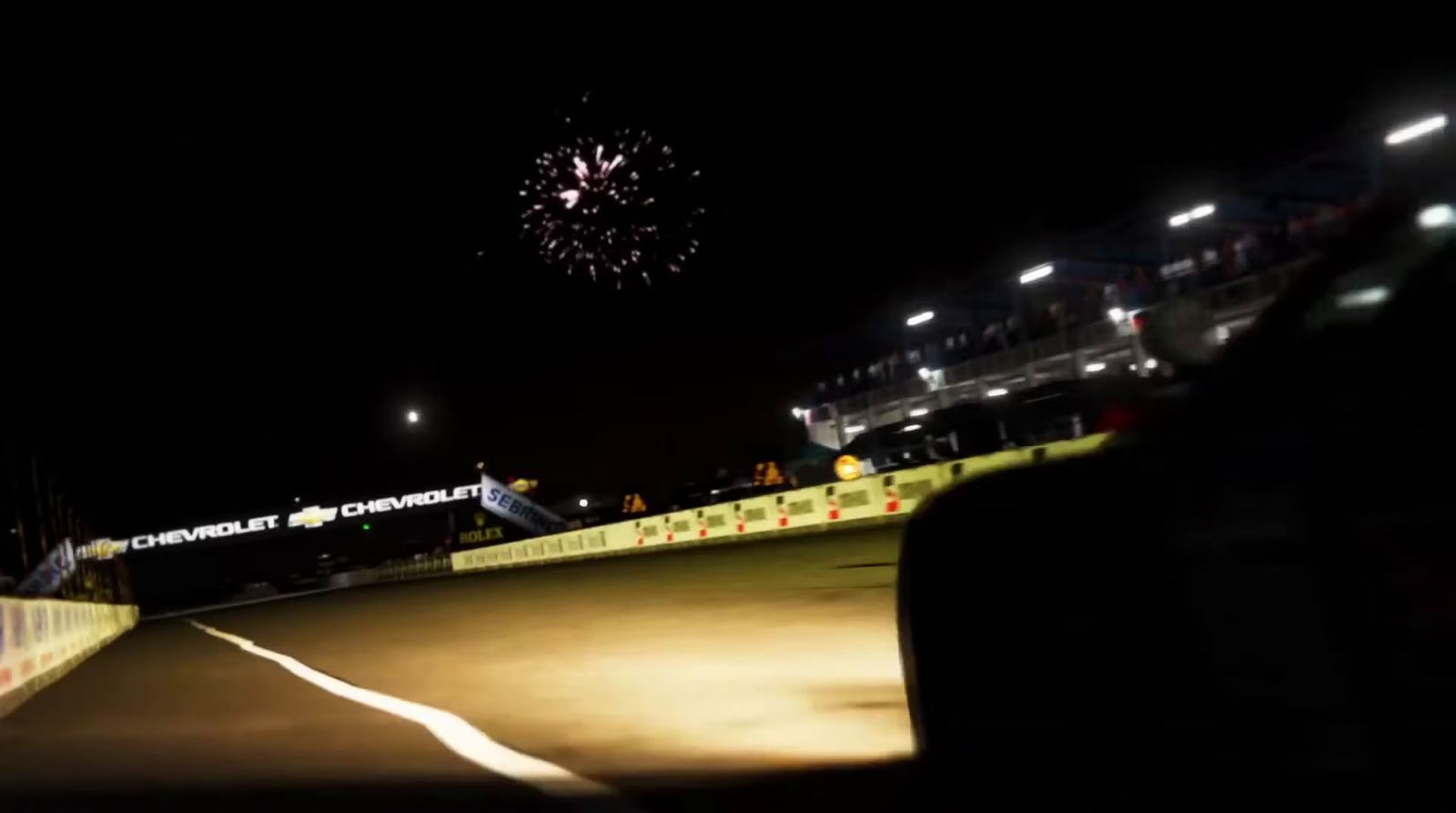 fireworks are lit up in the night sky above a race track