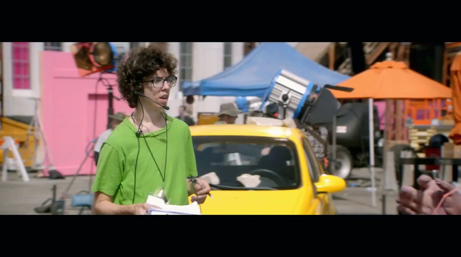 a woman in a green shirt standing next to a yellow car