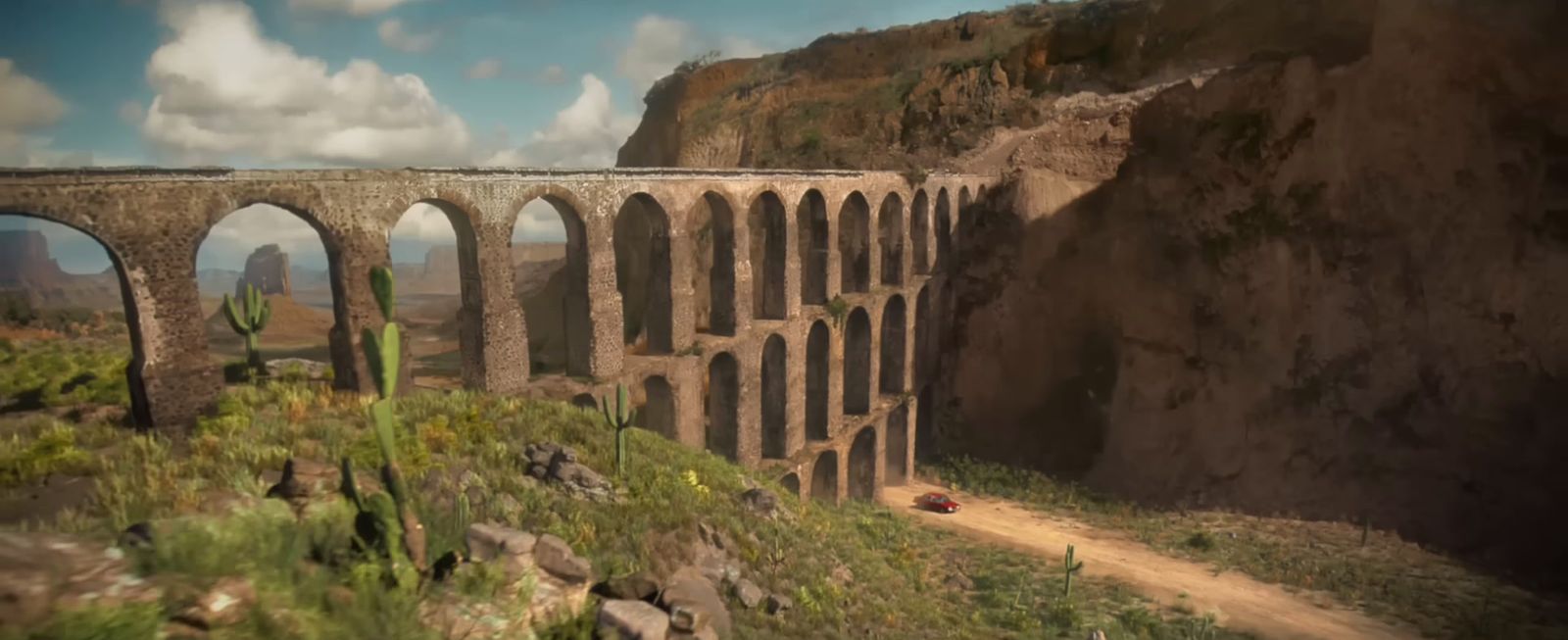 a car driving on a dirt road next to a bridge