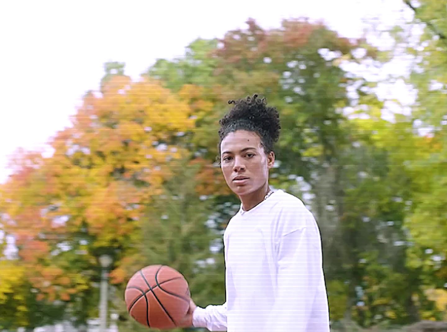 a young man holding a basketball in a park