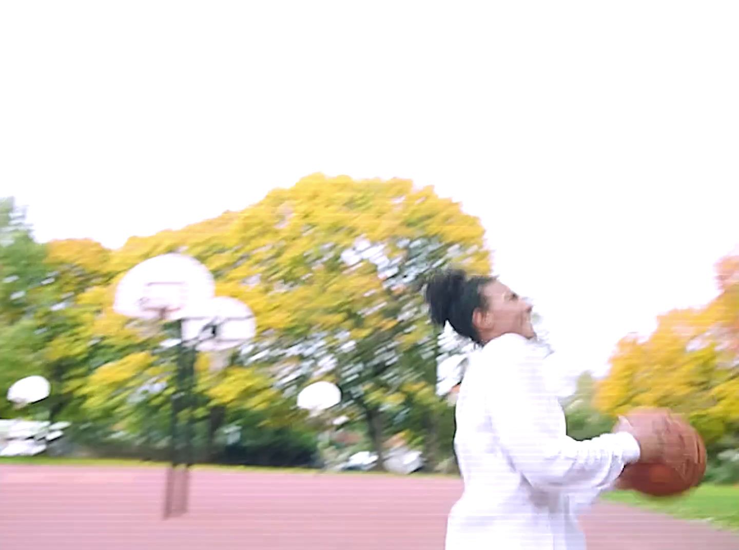 a woman holding a basketball in a park