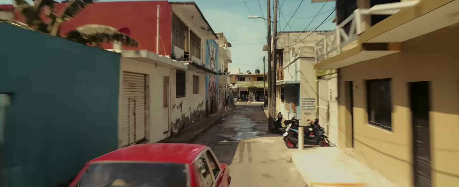 a red car driving down a street next to tall buildings