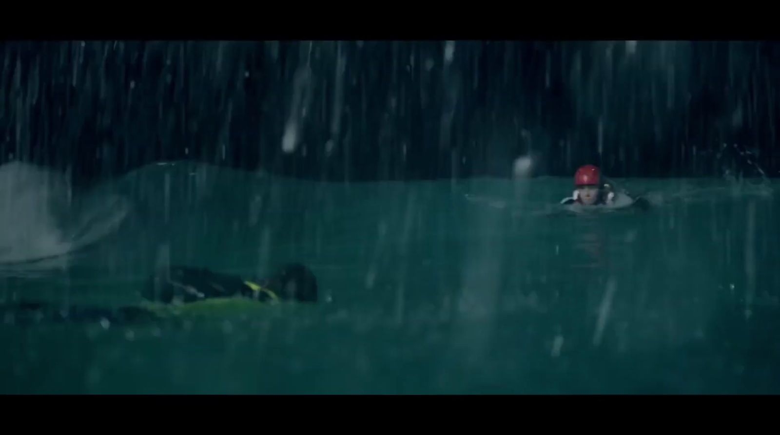 a person floating in a body of water in the rain