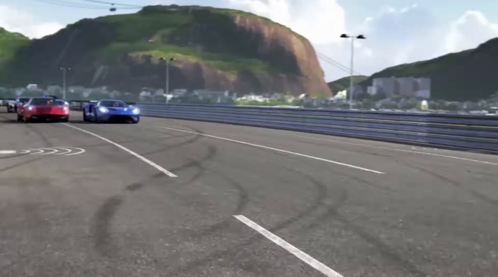 three cars driving on a race track with mountains in the background