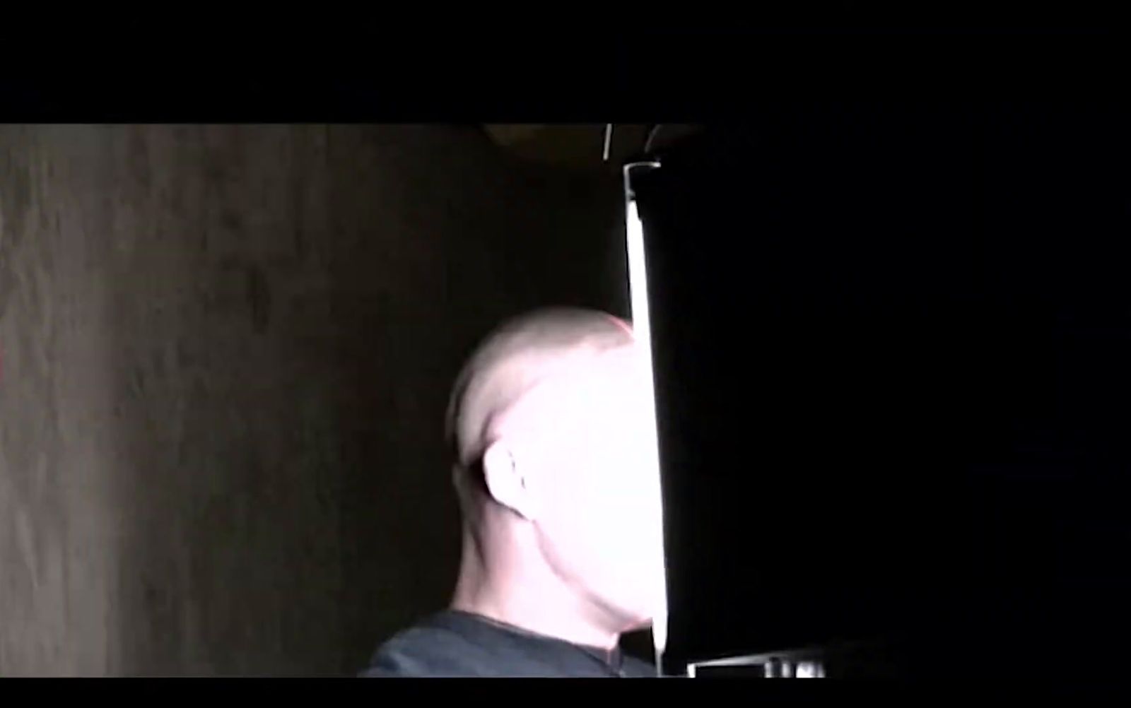 a man with a bald head standing in a dark room