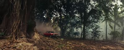 a red truck driving through a forest filled with trees