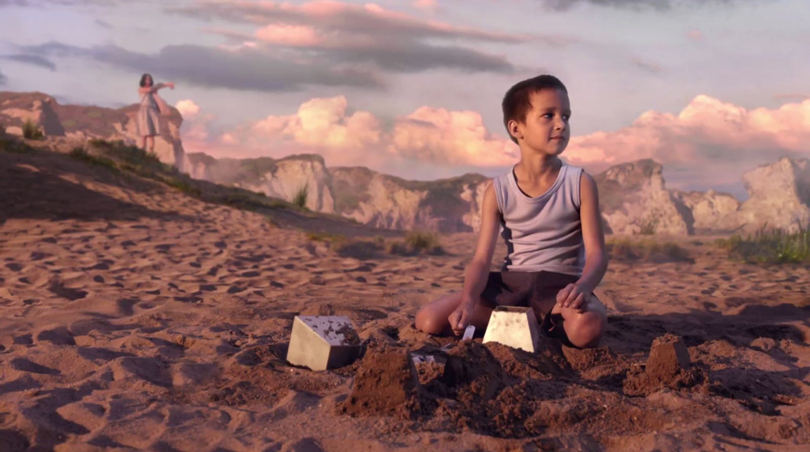 a young boy sitting on top of a sandy beach