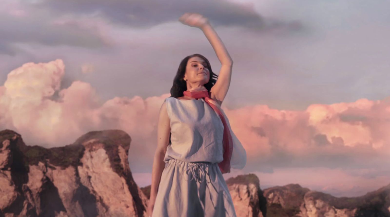 a woman standing on top of a mountain with her arms in the air