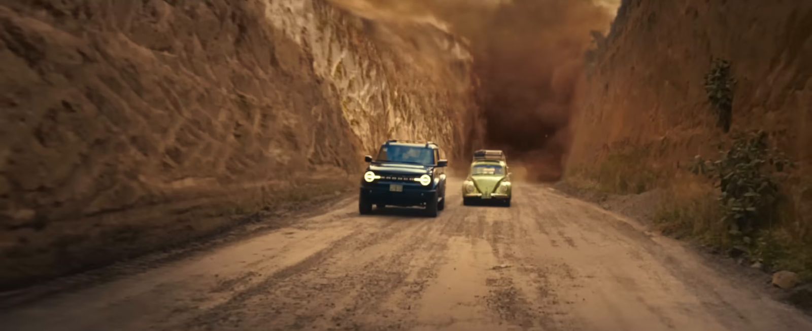 a couple of trucks driving down a dirt road