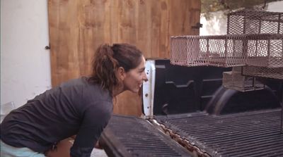 a woman bending over to look at a grill