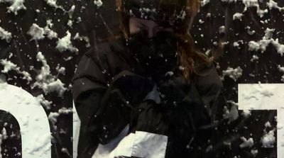 a woman standing in front of a sign covered in snow