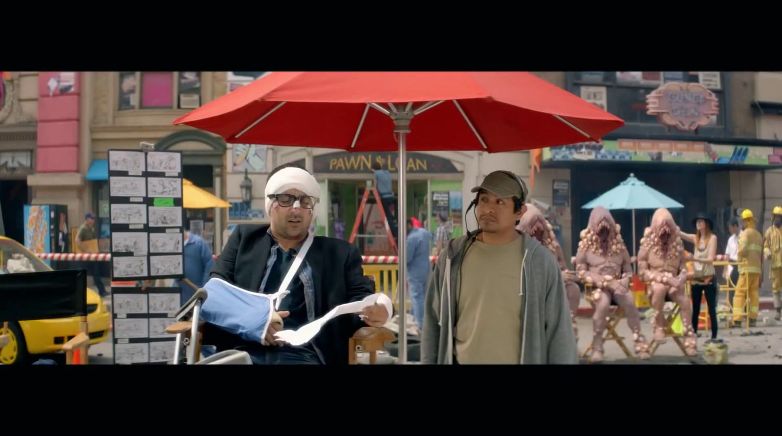 a couple of men standing next to each other under a red umbrella