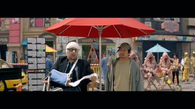 a couple of men standing next to each other under a red umbrella