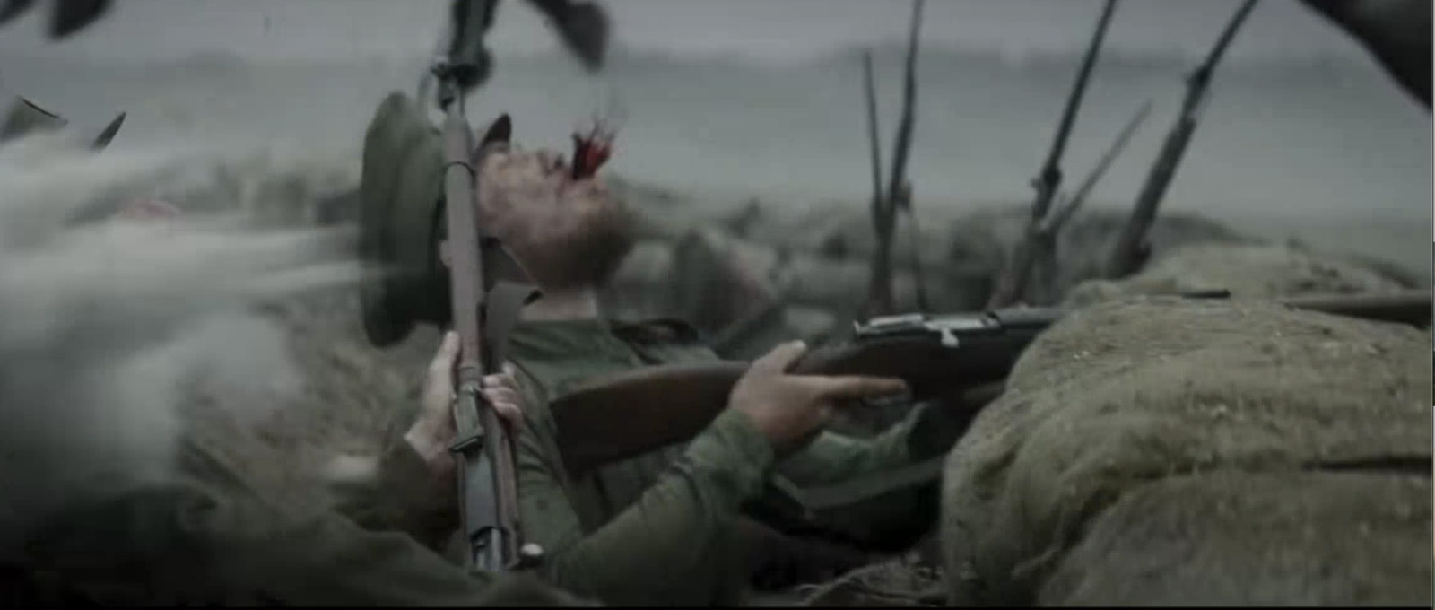 a man holding a rifle in front of a group of soldiers