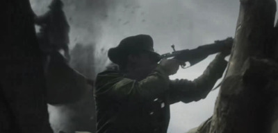 a man holding a rifle while standing next to a tree