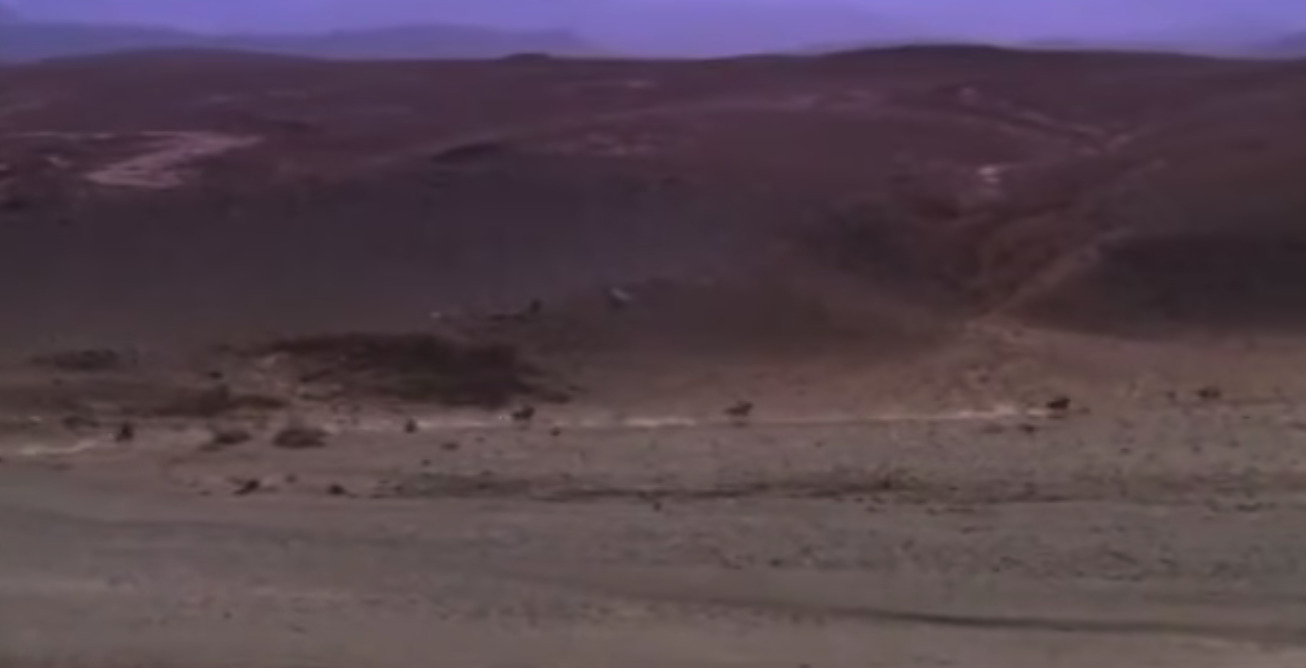 a blurry image of a desert with mountains in the background