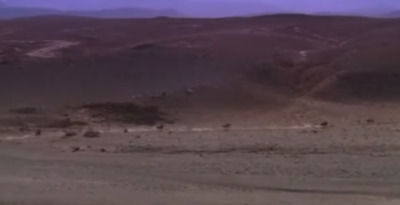 a blurry image of a desert with mountains in the background