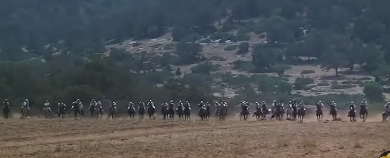 a group of people riding horses on a dirt field