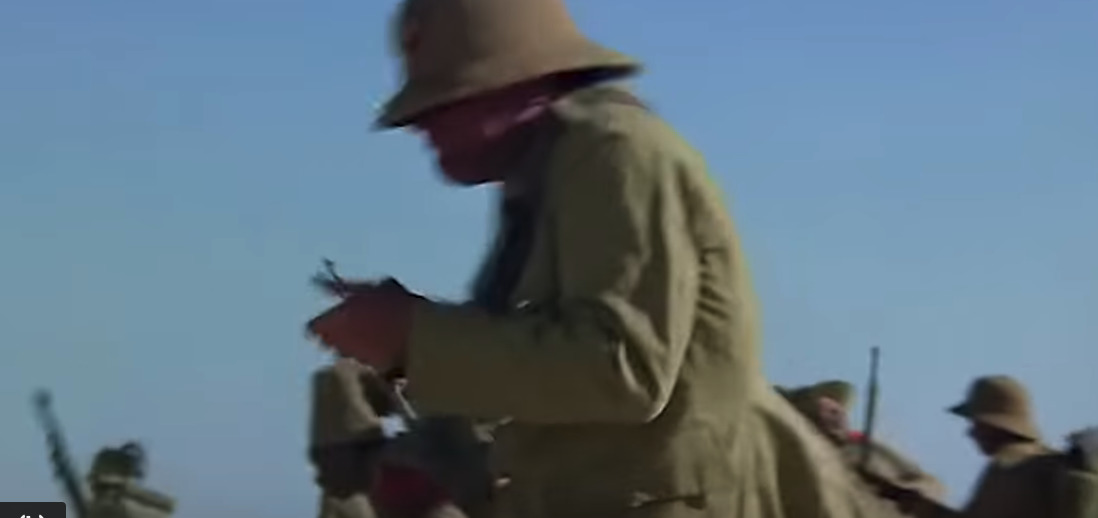 a man in a trench coat and hat holding a cell phone