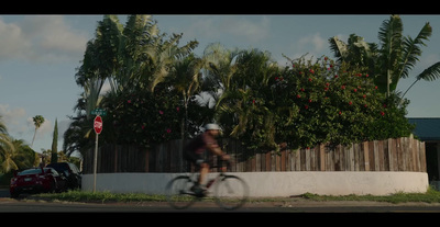 a man riding a bike down a street next to a fence