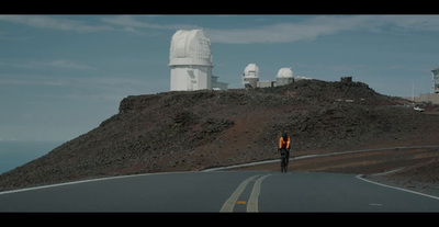 a man standing on the side of a road next to a hill