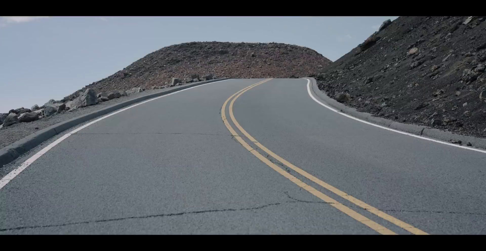 a curve in the road with a mountain in the background