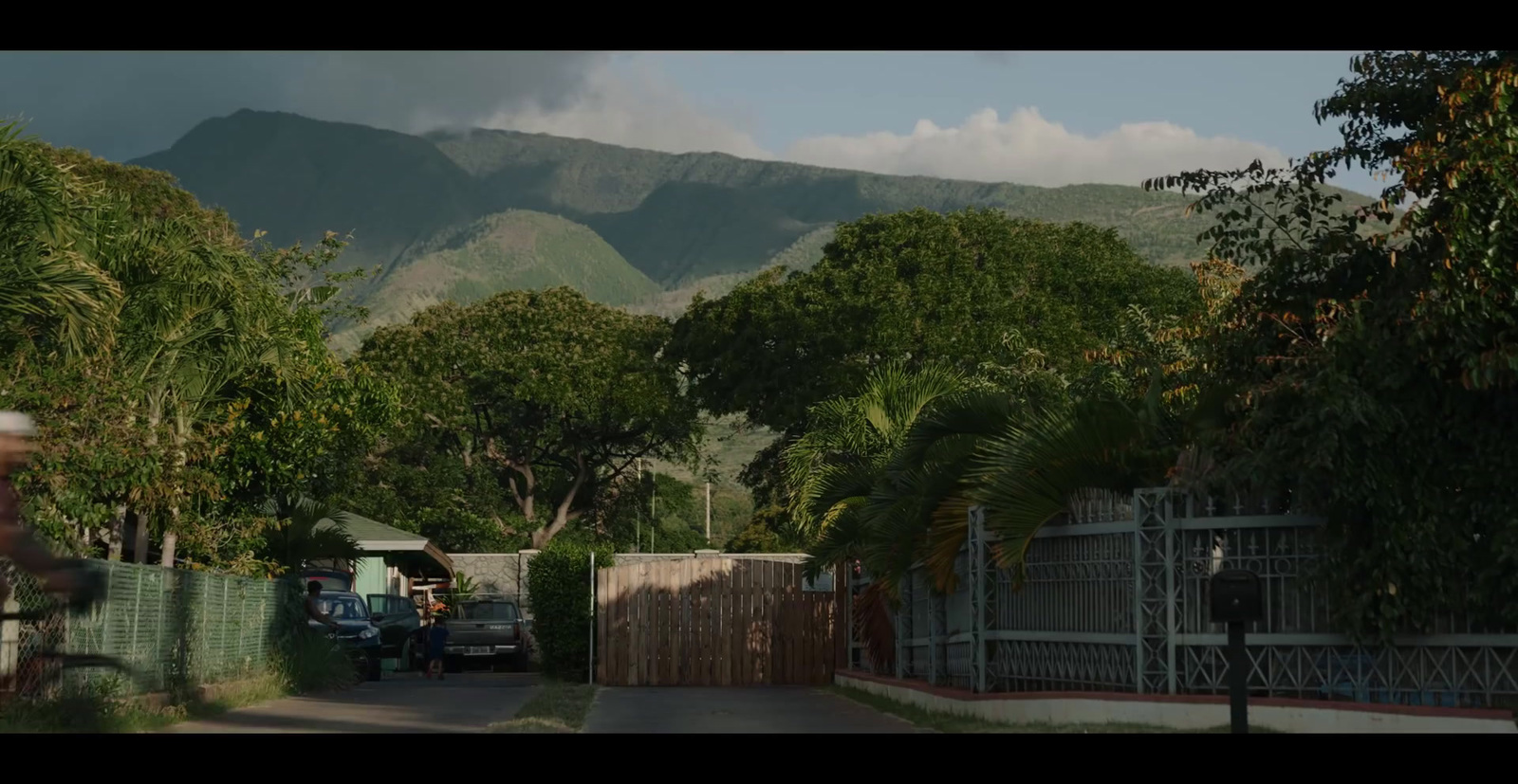 a man riding a bike down a street next to a lush green hillside