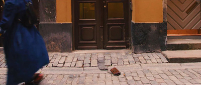 a woman walking down a street past a building