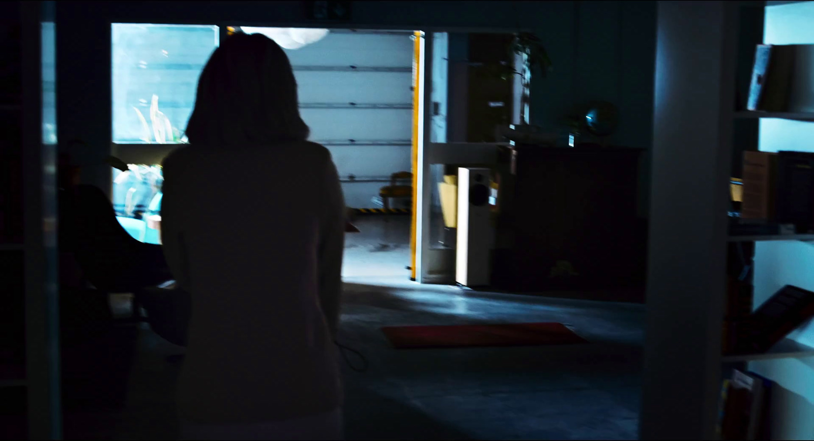 a woman standing in a dark room looking at a television