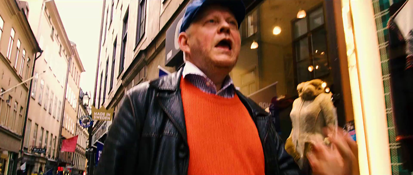 a man standing in front of a store window holding a bird