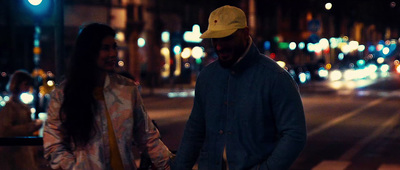 a man and a woman walking down a street at night