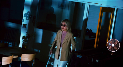 a woman in a suit and sunglasses standing in a dark room