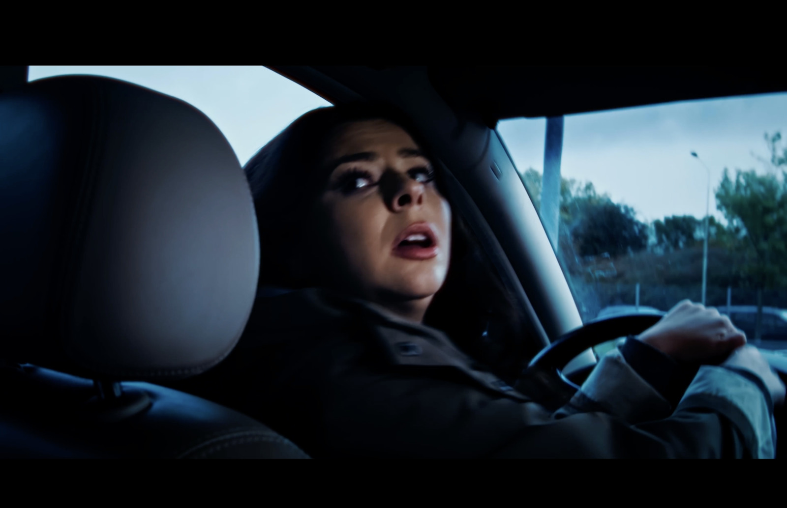 a woman driving a car with a surprised look on her face