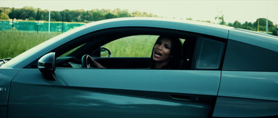 a woman driving a car in a grassy field