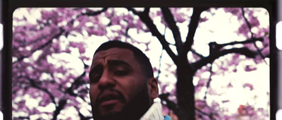 a man standing in front of a tree with purple flowers