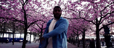 a man standing in front of a tree filled with pink flowers