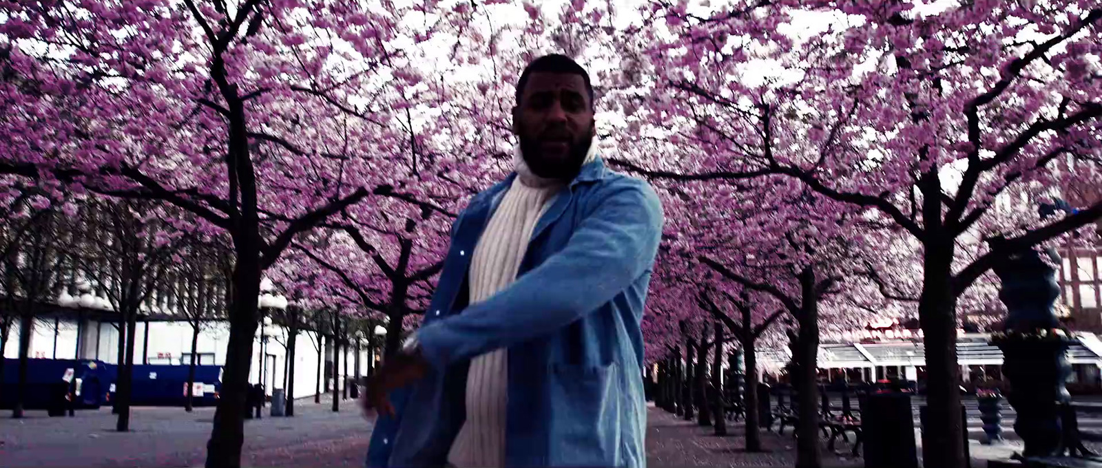 a man standing in front of a tree filled with pink flowers