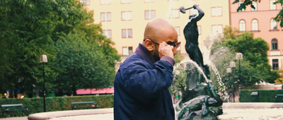 a bald man talking on a cell phone next to a fountain