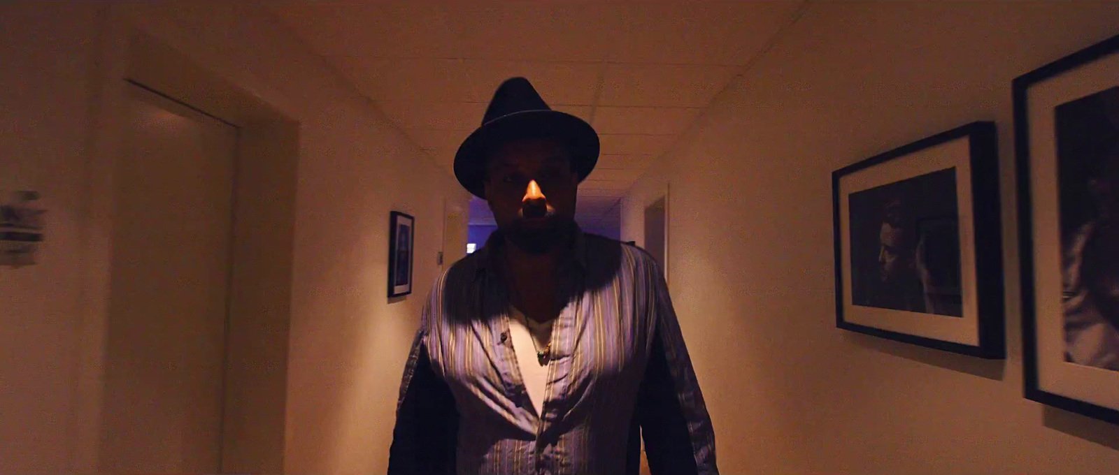 a man in a hat and vest standing in a hallway