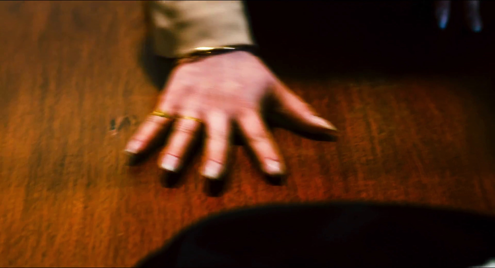 a person's hand resting on a wooden table