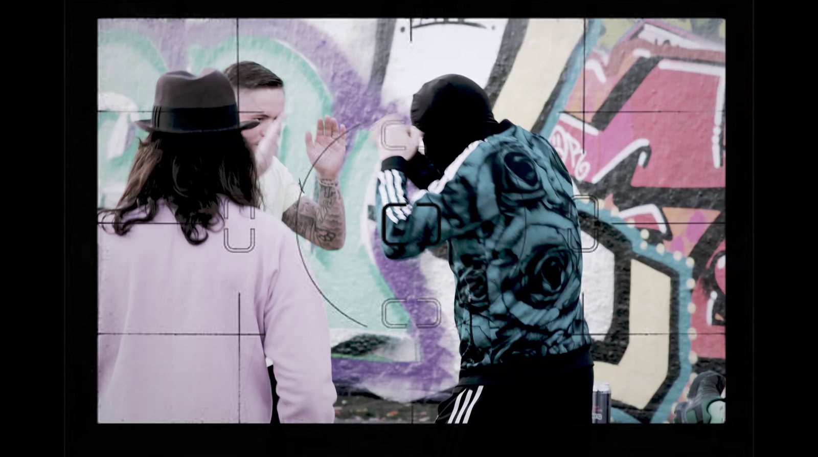 a man taking a picture of a woman in front of a graffiti wall