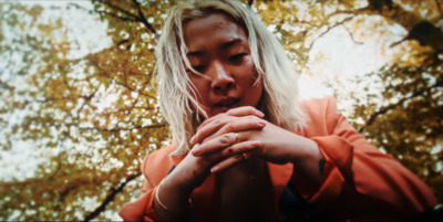 a woman holding her hands together in front of a tree